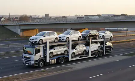 Car transporter with the Bedford, Bedfordshire, United Kingdom skyline behind it