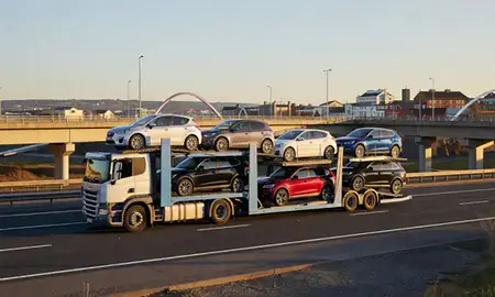 Car transporter with the Derry/Londonderry, County Londonderry, United Kingdom skyline behind it