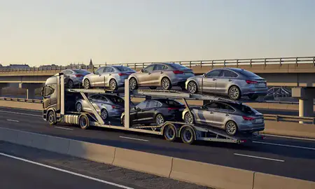 Car transporter with the Derby, Derbyshire, United Kingdom skyline behind it