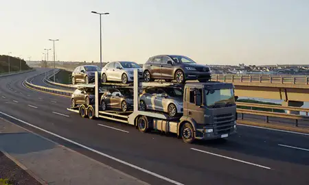 Car transporter with the Torquay, Devon, United Kingdom skyline behind it