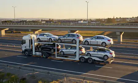 Car transporter with the Christchurch, Dorset, United Kingdom skyline behind it