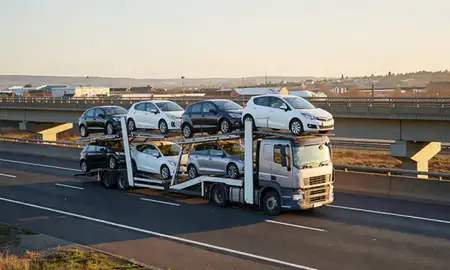 Car transporter with the Kilmarnock, East Ayrshire, United Kingdom skyline behind it