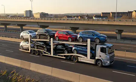 Car transporter with the Brentwood, Essex, United Kingdom skyline behind it