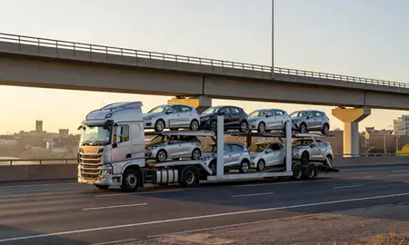 Car transporter with the Colchester, Essex, United Kingdom skyline behind it
