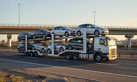 Car transporter with the Chadderton, Greater Manchester, United Kingdom skyline behind it