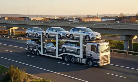 Car transporter with the Eccles, Greater Manchester, United Kingdom skyline behind it