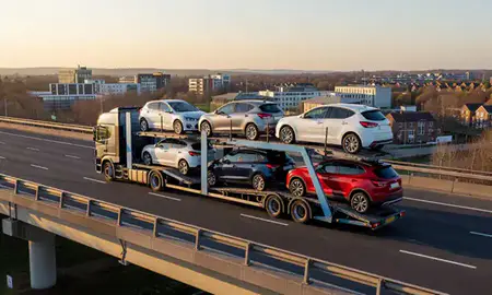 Car transporter with the Welwyn Garden City, Hertfordshire, United Kingdom skyline behind it