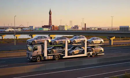Car transporter with the Blackpool, Lancashire, United Kingdom skyline behind it