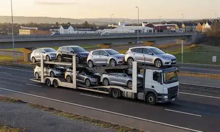 Car transporter with the Airdrie, North Lanarkshire, United Kingdom skyline behind it