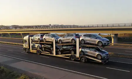Car transporter with the Scarborough, North Yorkshire, United Kingdom skyline behind it