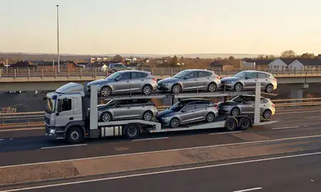 Car transporter with the Sutton-in-Ashfield, Nottinghamshire, United Kingdom skyline behind it