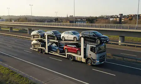 Car transporter with the Walton-on-Thames, Surrey, United Kingdom skyline behind it