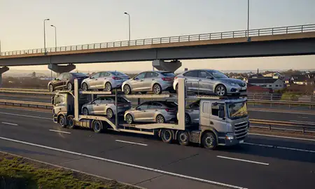 Car transporter with the Jarrow, Tyne and Wear, United Kingdom skyline behind it