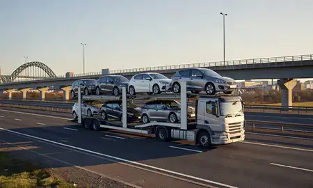Car transporter with the Newcastle upon Tyne, Tyne and Wear, United Kingdom skyline behind it