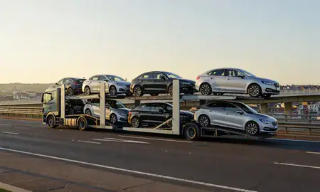 Car transporter with the Neath, West Glamorgan, United Kingdom skyline behind it