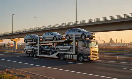 Car transporter with the Port Talbot, West Glamorgan, United Kingdom skyline behind it