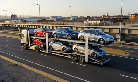 Car transporter with the Dudley, West Midlands, United Kingdom skyline behind it