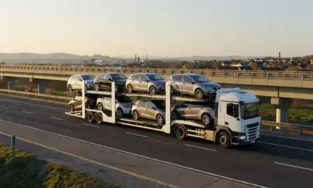 Car transporter with the Batley, West Yorkshire, United Kingdom skyline behind it