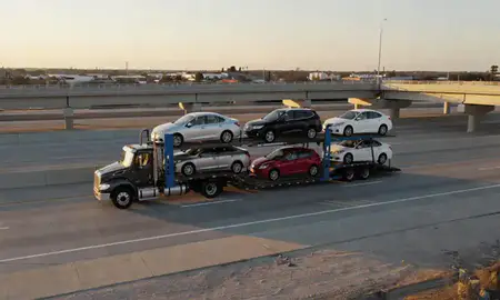 Car transporter with the Dothan, Alabama, United States skyline behind it