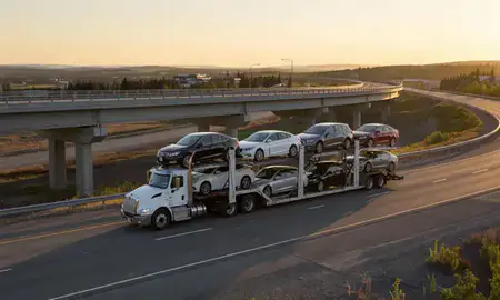 Car transporter with the Farmers Loop, Alaska, United States skyline behind it