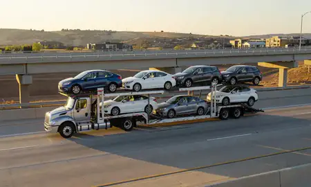 Car transporter with the Highlands Ranch, Colorado, United States skyline behind it