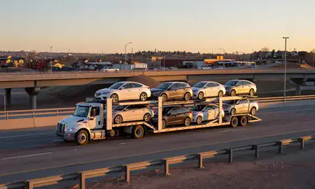 Car transporter with the Westminster, Colorado, United States skyline behind it