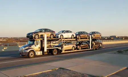 Car transporter with the New Castle, Delaware, United States skyline behind it
