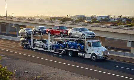 Car transporter with the Schofield Barracks, Hawaii, United States skyline behind it