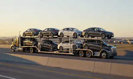 Car transporter with the Fort Dodge, Iowa, United States skyline behind it