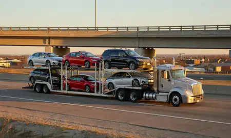 Car transporter with the Andover, Kansas, United States skyline behind it