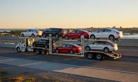 Car transporter with the Lewiston, Maine, United States skyline behind it