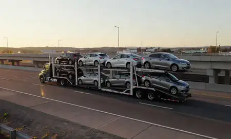 Car transporter with the Saco, Maine, United States skyline behind it