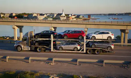 Car transporter with the York Harbor, Maine, United States skyline behind it