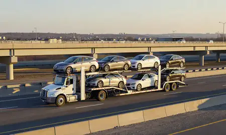 Car transporter with the Newton, Massachusetts, United States skyline behind it