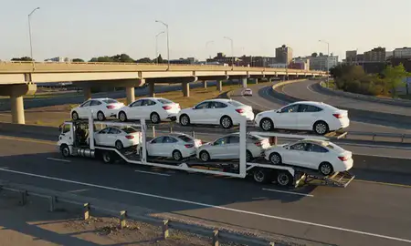 Car transporter with the Peabody, Massachusetts, United States skyline behind it