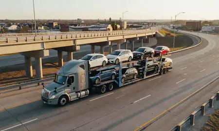Car transporter with the Norfolk, Nebraska, United States skyline behind it