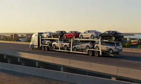 Car transporter with the Laconia, New Hampshire, United States skyline behind it