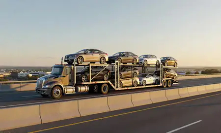 Car transporter with the Pinardville, New Hampshire, United States skyline behind it
