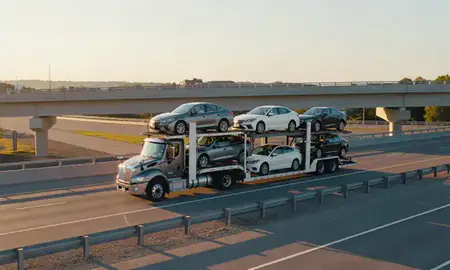 Car transporter with the South Hooksett, New Hampshire, United States skyline behind it
