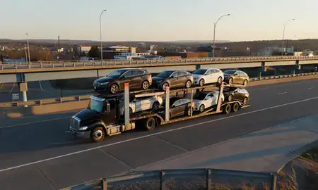 Car transporter with the Glens Falls, New York, United States skyline behind it