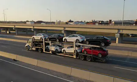 Car transporter with the Greenville, North Carolina, United States skyline behind it
