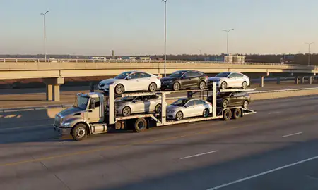 Car transporter with the Monroe, North Carolina, United States skyline behind it