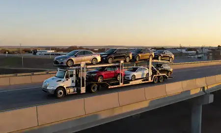 Car transporter with the Belcourt, North Dakota, United States skyline behind it