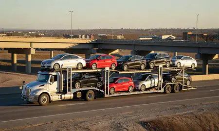 Car transporter with the Grand Forks, North Dakota, United States skyline behind it