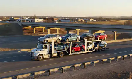 Car transporter with the Mandan, North Dakota, United States skyline behind it