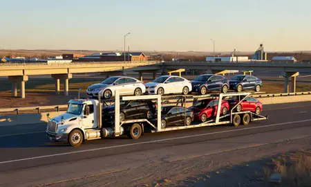 Car transporter with the Stanley, North Dakota, United States skyline behind it