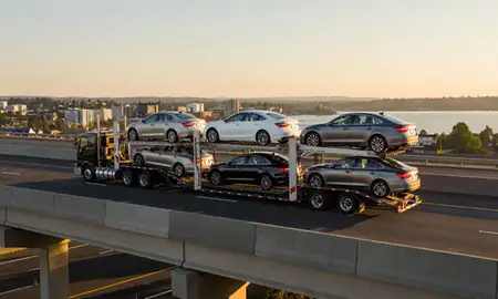 Car transporter with the Lake Oswego, Oregon, United States skyline behind it