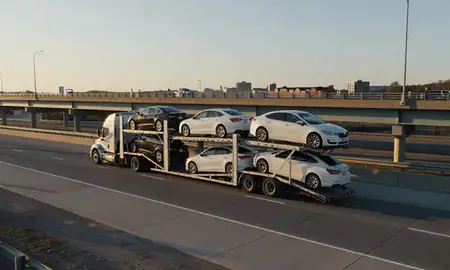 Car transporter with the Norristown, Pennsylvania, United States skyline behind it