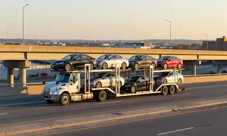 Car transporter with the Central Falls, Rhode Island, United States skyline behind it