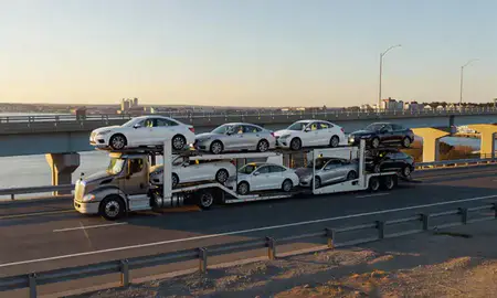 Car transporter with the Newport, Rhode Island, United States skyline behind it